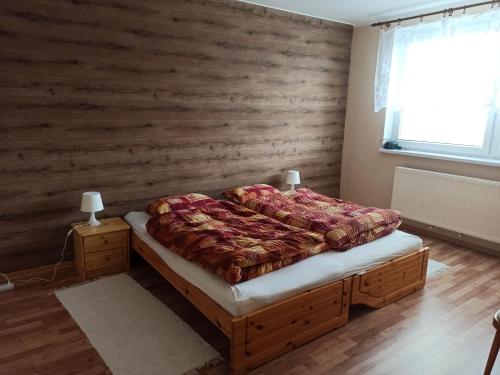 - une chambre avec un lit et un mur en bois dans l'établissement Apartmán Tatranská Lomnica, à Tatranská Lomnica