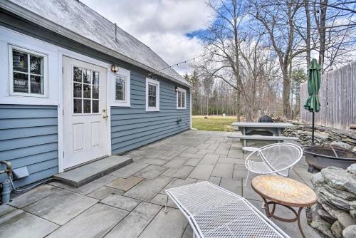 a patio with a blue house and a table and chairs at Charming Cottage with Yard - 2 Mi to Tinker St! in Woodstock