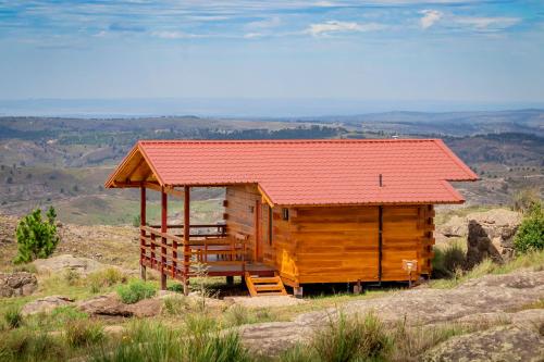 a wooden cabin with a red roof on a hill at Alma Serrana - Suites de montaña! in La Cumbrecita