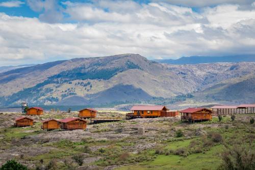 a group of houses in a field with mountains in the background at Alma Serrana - Suites de montaña! in La Cumbrecita