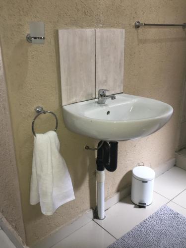 a bathroom with a white sink and a towel at Asante’s Guest House in Calcutta