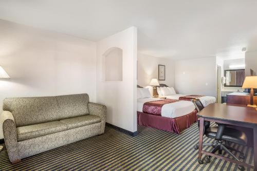 a hotel room with a bed and a couch and a desk at Americas Best Value Inn New Braunfels in New Braunfels