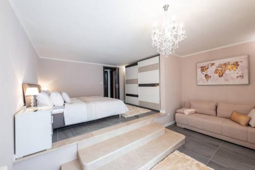 a bedroom with a bed and a couch and a chandelier at Deluxe Apartment Unique-With Private Heated Pool in Cavtat