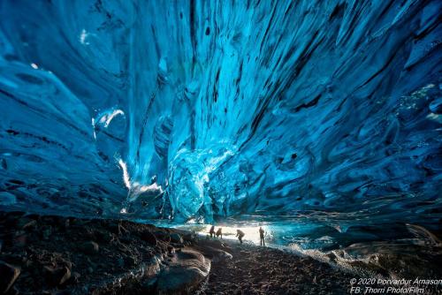 a large blue ice cave with people in it at Höfn Hostel in Höfn