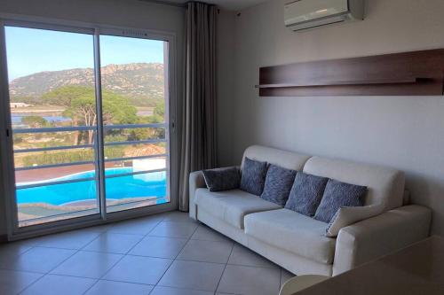 un salon avec un canapé et une grande fenêtre dans l'établissement Salina Bay Porto Vecchio, à Porto-Vecchio