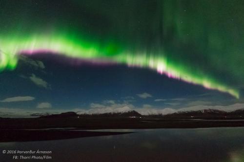 an aurora in the sky over a body of water at Höfn Hostel in Höfn