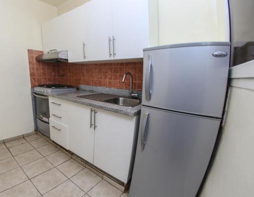 a kitchen with white cabinets and a stainless steel refrigerator at Acuarium Suite Resort in Santo Domingo