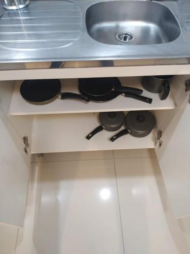 uma gaveta de cozinha com panelas e frigideiras debaixo de um lavatório em Apartamento Tranquilo Próximo ao Aeroporto. Sem taxa de limpeza em São José dos Pinhais