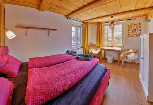 a bedroom with a large bed and a desk at Uelis-Stöckli-Gästezimmer auf belebtem Bauernhof mit Hotpot und Alpakatrekking 