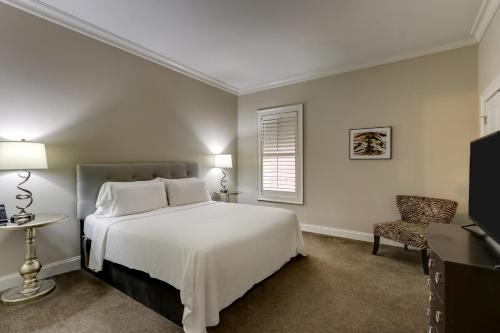a bedroom with a white bed and a chair at The Mantissa Hotel in Hartsville