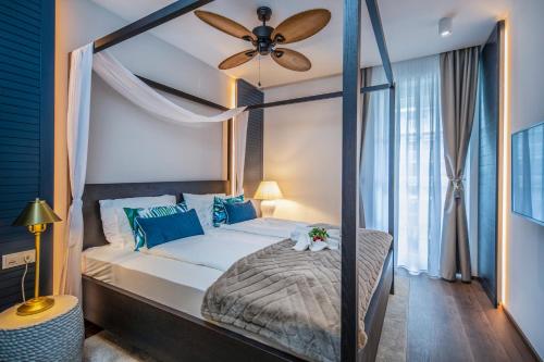 a bedroom with a canopy bed with a ceiling fan at BalaLake Resort in Szántód
