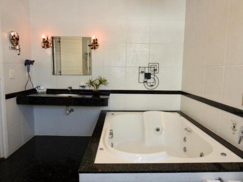 a bathroom with a large tub and a sink at Constantino Hotel e Eventos in Juiz de Fora