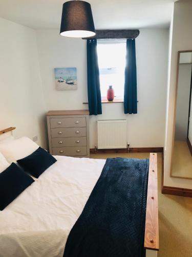 a bedroom with a bed with blue curtains and a window at New for 2021 Welcome to Violet Cottage in Combe Martin