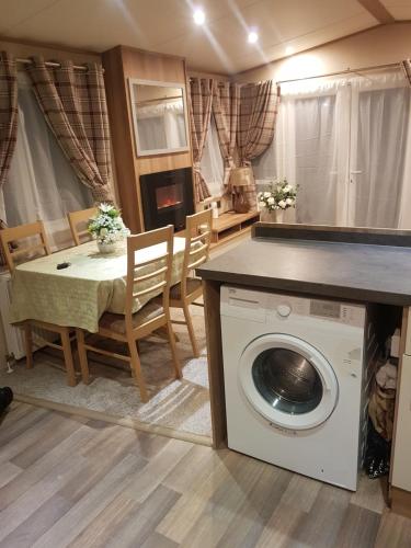 a living room with a table and a washing machine at Sunningdale Sanctuary in Jaywick Sands