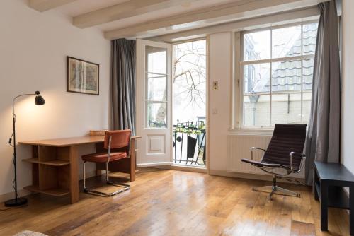 a living room with a desk and chairs and windows at Kloveniers Studio in Amsterdam