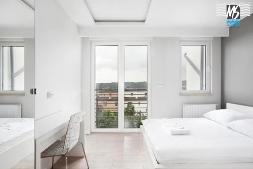 biała sypialnia z białym łóżkiem i oknem w obiekcie MS Apartments Green Hill II w mieście Gdynia