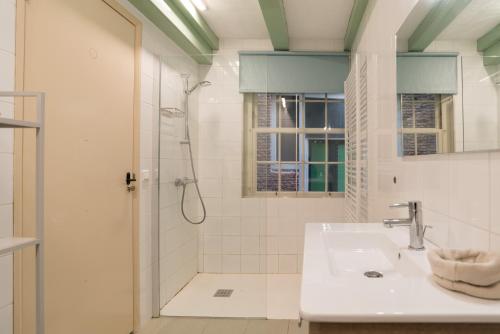 a white bathroom with a shower and a sink at Kloveniers Studio in Amsterdam