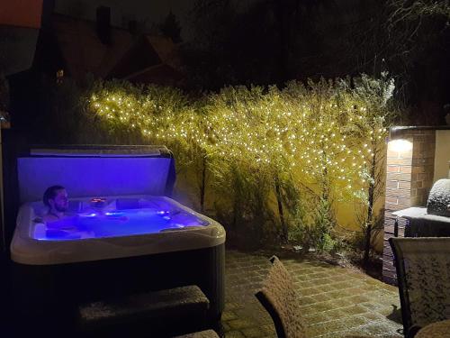 a man in a jacuzzi tub in a backyard with lights at Helsinkis in Anykščiai