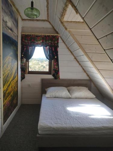 a bed in a small room with a window at LEŚNY DWOREK 2 in Wołkowyja