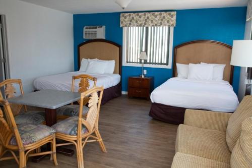 a hotel room with two beds and a couch at Daytona Dream Inn By AmeriVu in Daytona Beach