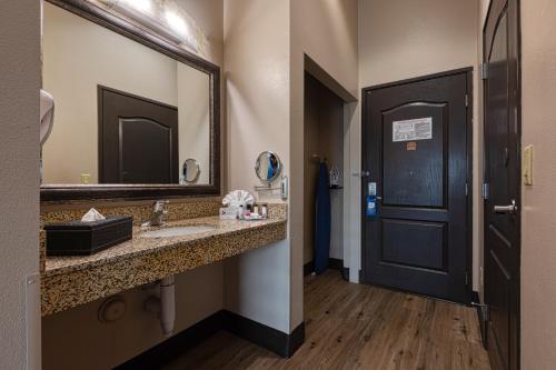 a bathroom with a sink and a mirror and a door at The Azure Hotel in Mesa