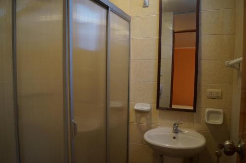 a bathroom with a sink and a shower with a mirror at CasaHotel El Tambo Huancayo in Huancayo