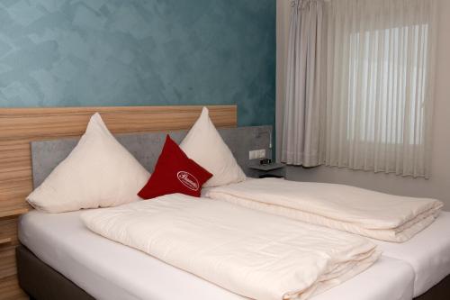 two beds in a room with white and red pillows at Landgasthof Zur Erholung in Breitscheid