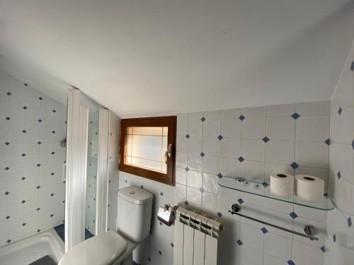 a white bathroom with a toilet and a window at Hostal El Horno in Molinaseca