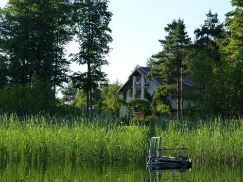 a boat sitting in the water in front of a house at Kosewo 78 Family Hotel & Spa in Kosewo