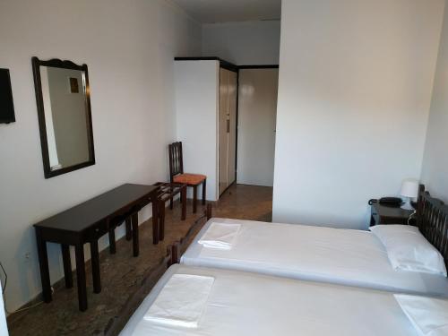 a room with two beds and a table and a mirror at Daskalio Beach Hotel in Keratea