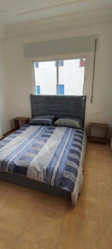 um quarto com uma cama com um edredão azul e 2 janelas em El balcón del mediterráneo em M'diq