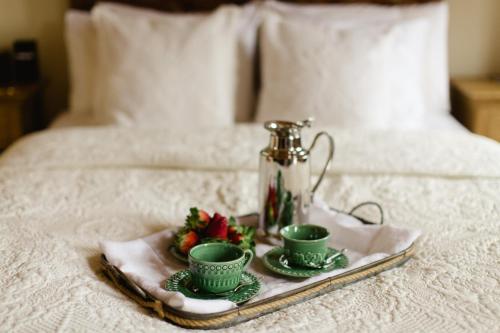 un plateau avec deux tasses vertes et des fraises sur un lit dans l'établissement Casa Bohemia, à Sintra