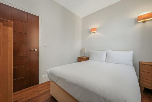 a bedroom with a white bed and a wooden cabinet at Tavistock Place Apartments in London