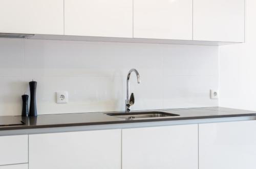 a kitchen with white cabinets and a sink at Pico Do Feliz - The Penthouse & The Village By Silver Prop in Nazaré