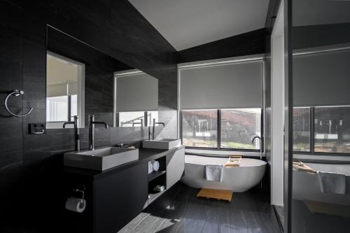 a black bathroom with a tub and a sink at The Cove Tasmania in Devonport