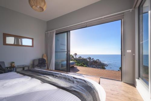 a bedroom with a large window with a view of the ocean at The Cove Tasmania in Devonport