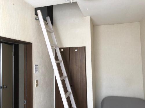 a room with a ladder next to a door at 竜ケ崎駅そばのゲストハウスM＆M３ in Ryūgasaki