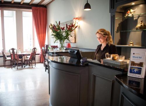 
a woman standing in front of a counter in a restaurant at Best Western Plus City Centre Hotel Den Bosch in Den Bosch
