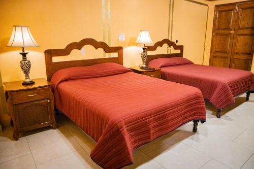 a bedroom with two beds with red sheets and lamps at Cuartel 1914 - Hotel Boutique in Zacatecas