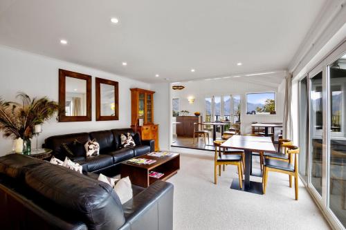 a living room with a leather couch and a table at Queenstown House Bed & Breakfast and Apartments in Queenstown