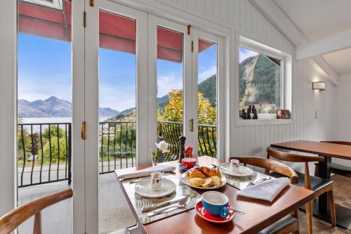 a dining room with a table and chairs and windows at Queenstown House Bed & Breakfast and Apartments in Queenstown