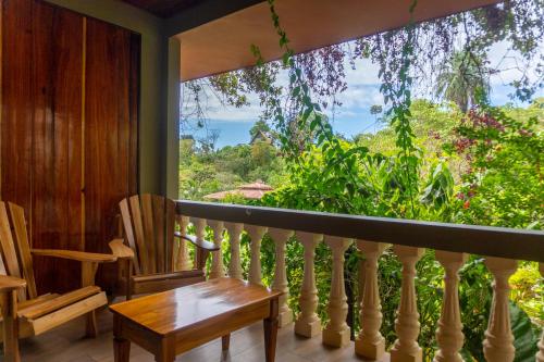 einen Balkon mit einem Tisch und Stühlen sowie einem großen Fenster in der Unterkunft Jacamar Corcovado Drake Bay in Drake