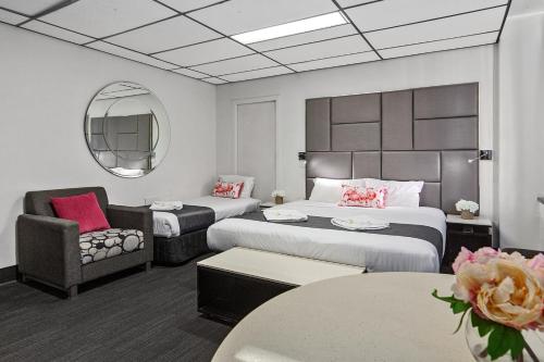 a hotel room with two beds and a chair at Cosmo on Bank in Adelaide
