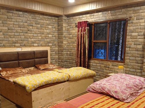 a bedroom with two beds and a window at Mehdudia Guest House in Shimla