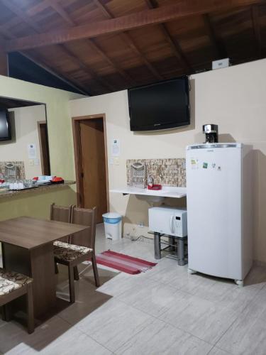 a kitchen with a table and a white refrigerator at Pousada TRUFFIMAR Ilhabela in Ilhabela