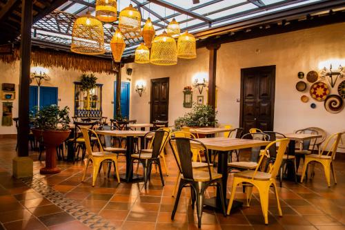 a restaurant with tables and yellow chairs and chandeliers at Hotel Boutique Casa Grande in Piedecuesta