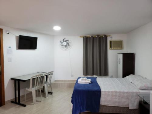 a hotel room with a bed and a table and a desk at Pousada TRUFFIMAR Ilhabela in Ilhabela