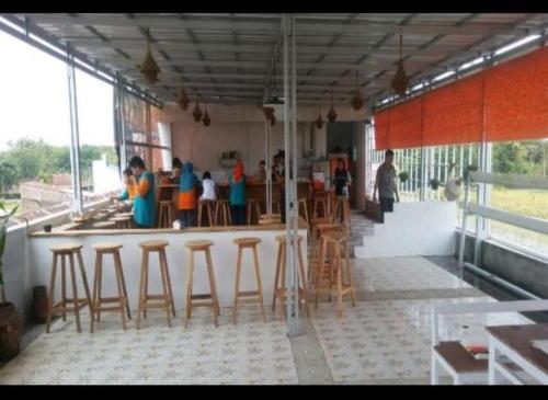 um bar com bancos de madeira e um grupo de pessoas em D'SAWAH GUESTHOUSE em Klaten