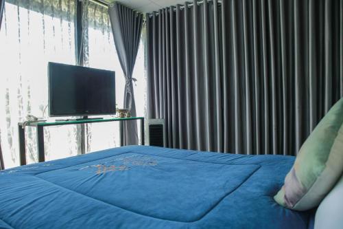 a bedroom with a blue bed and a flat screen tv at Dalat Terrasse Des Roses Villa in Da Lat