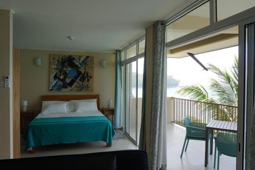 a bedroom with a bed and a balcony at Maka Bay Self Catering in Victoria